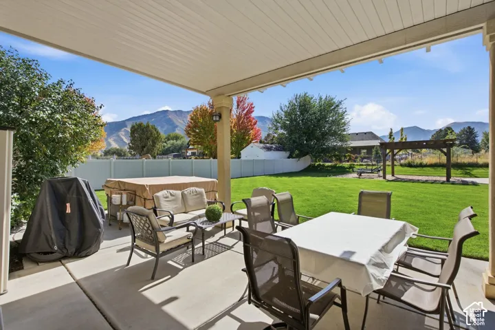 Covered patio featuring concrete flooring and a white vinyl privacy fence