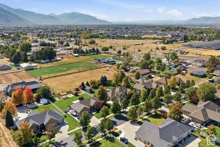 Expansive neighborhood with diverse residential architecture and mature trees, set against a backdrop of mountains and open fields