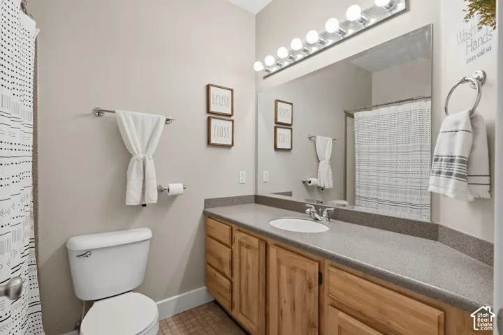 Bathroom featuring a light-toned vanity with a built-in sink, wood-finish cabinetry, and a large wall mirror