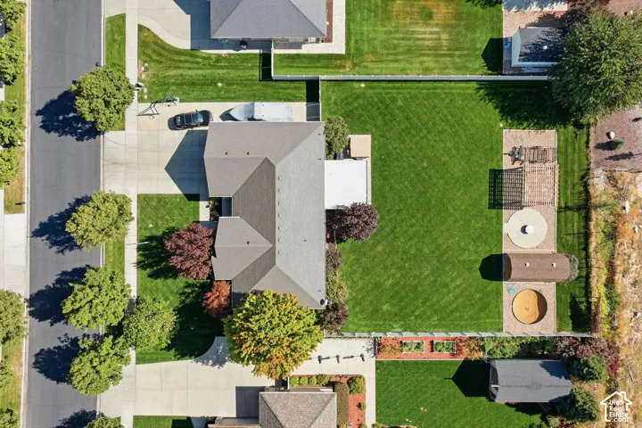 Expansive green lawn, mature trees, concrete driveway, paved patio area, and a storage shed