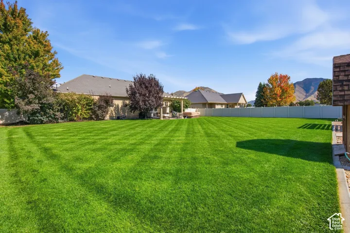Expansive green lawn with mature trees and a white privacy fence