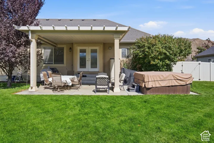 Expansive backyard featuring a covered patio, concrete hardscaping, and a white vinyl fence