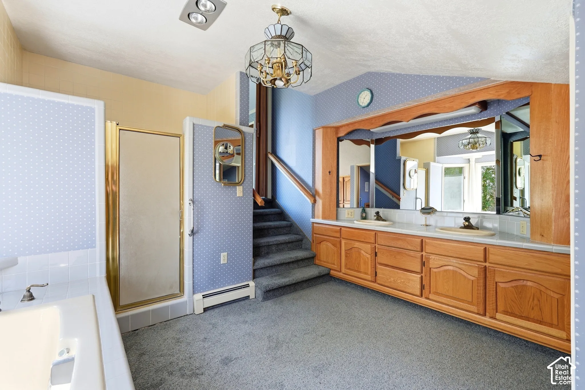 Dual vanity with wood cabinetry and undermount sinks, full-width mirror, and a built-in bathtub with a gold-framed shower enclosure