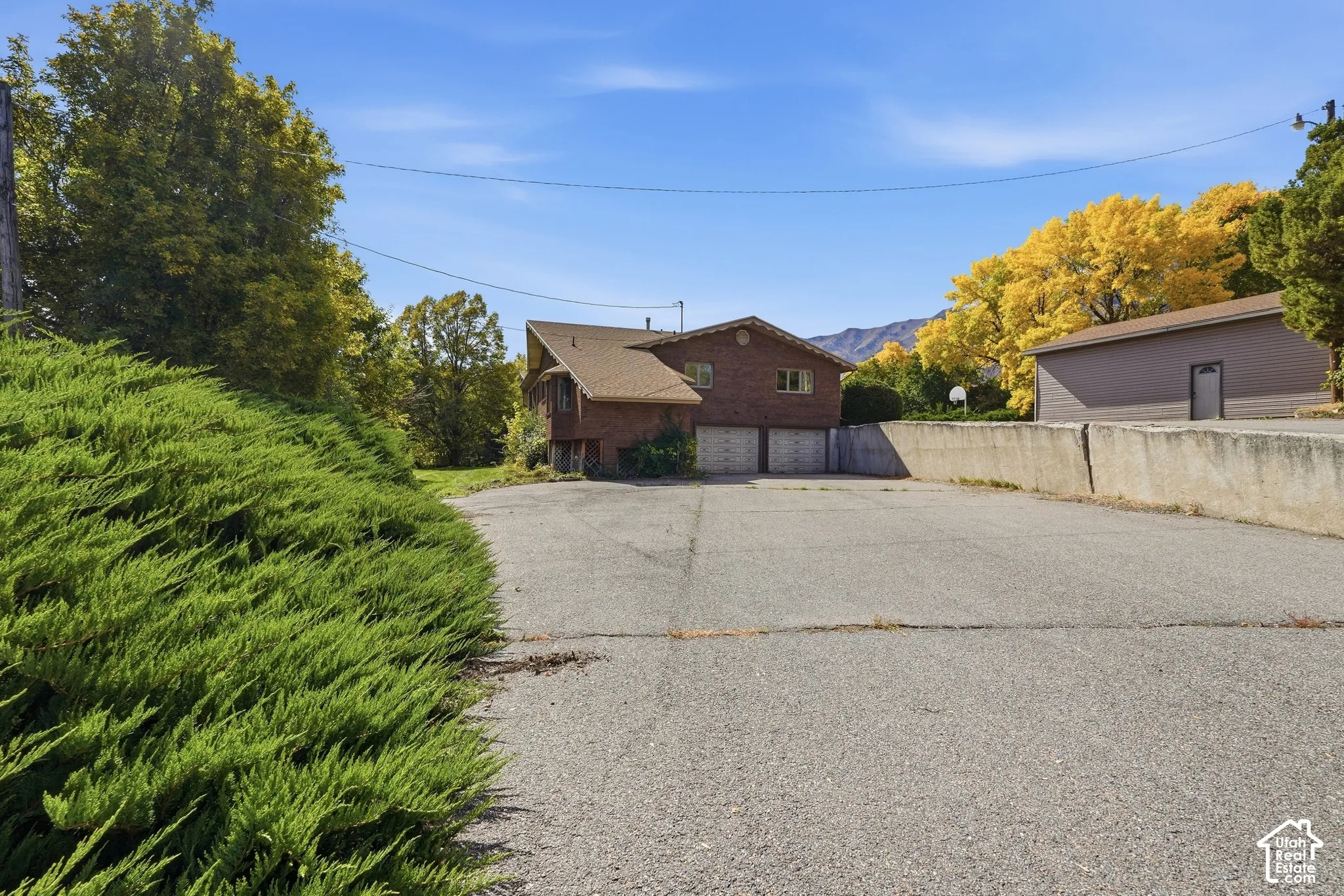 Brick exterior residence with a two-car garage, asphalt driveway, and mature landscaping