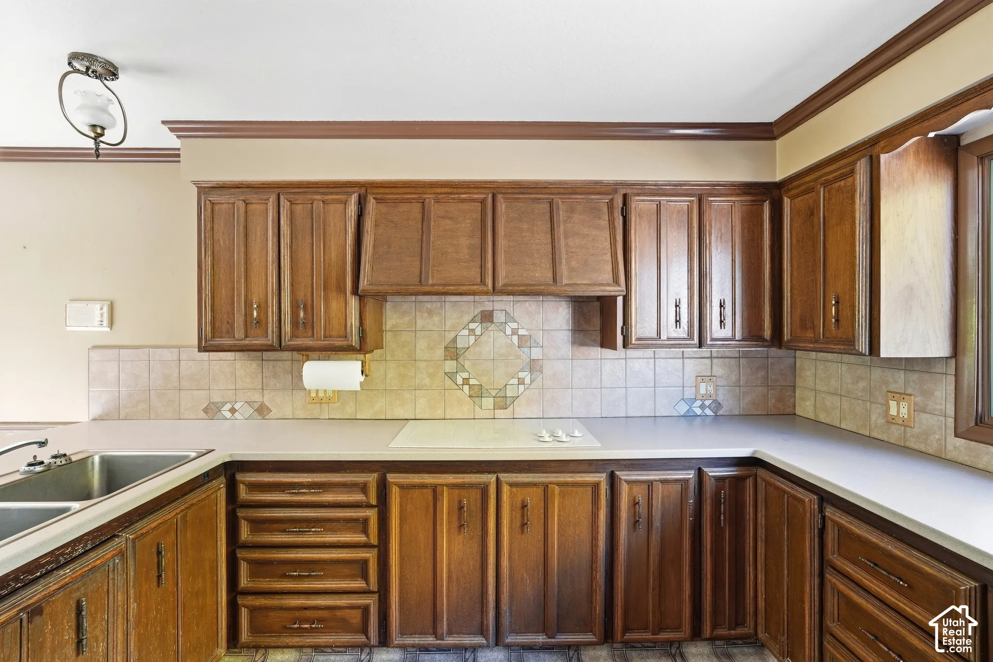 Wood cabinetry with varied door styles, light-toned countertops, and a tiled backsplash with a decorative inset