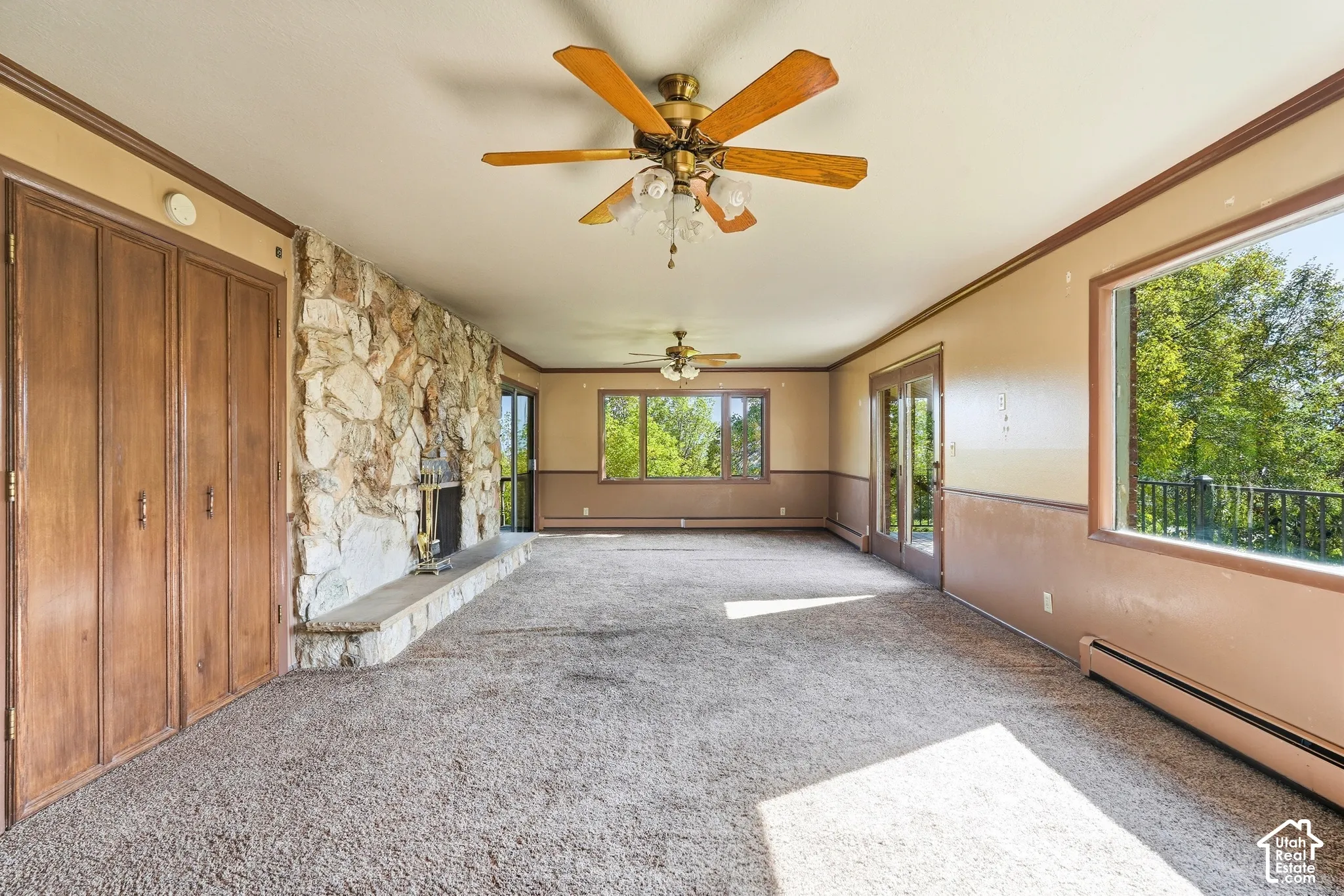 Expansive living area featuring a stone accent wall, fireplace with stone hearth, wood-paneled closet doors, and multiple windows