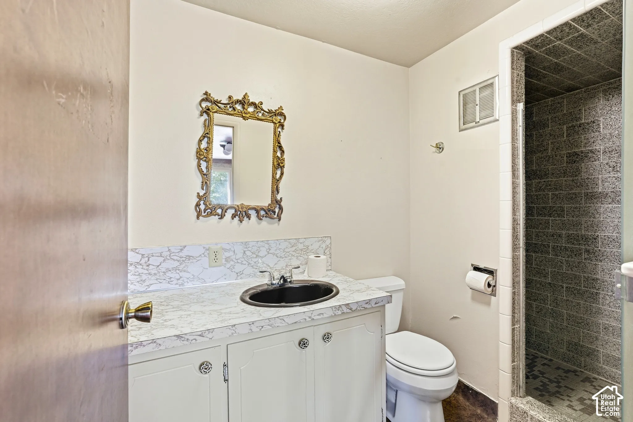 Vanity with a black basin sink and a decorative gold-tone mirror