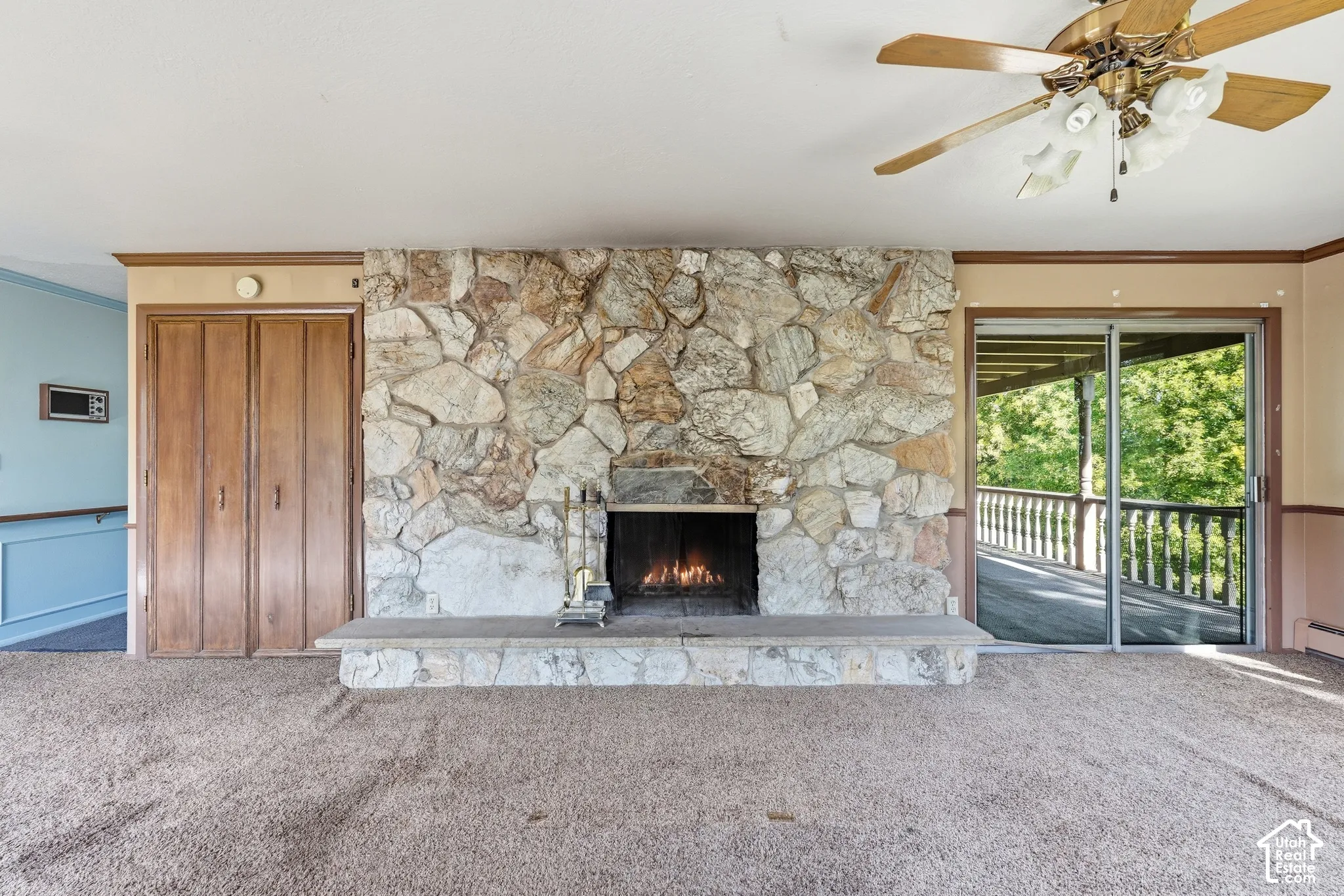 Stone-clad fireplace with a raised hearth, wood-finish bi-fold closet doors, and sliding glass door leading to an outdoor deck