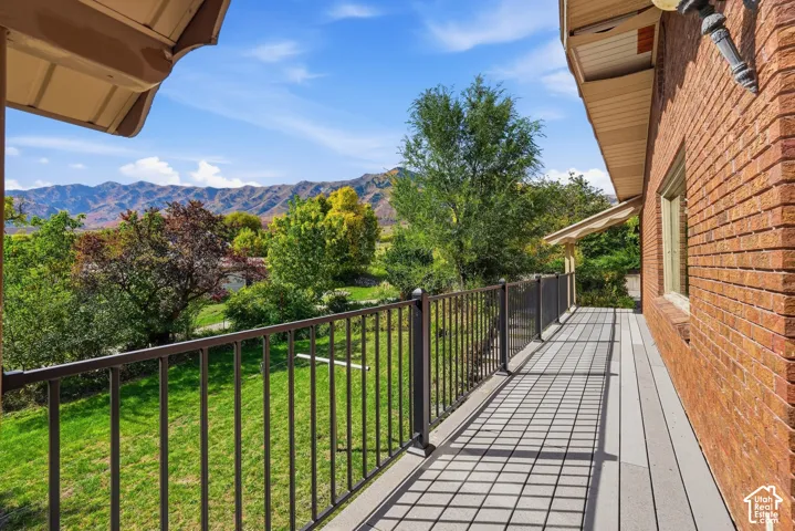 Expansive outdoor deck with composite decking and metal railing, featuring a brick exterior and a clear mountain backdrop