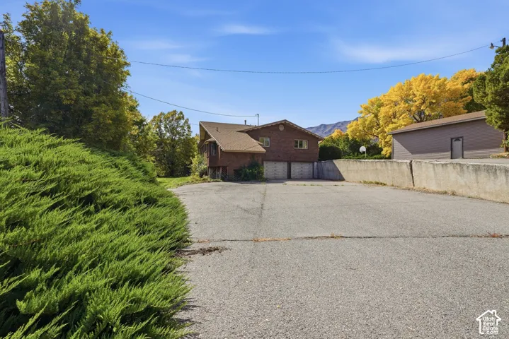 Brick exterior residence with a two-car garage, asphalt driveway, and mature landscaping