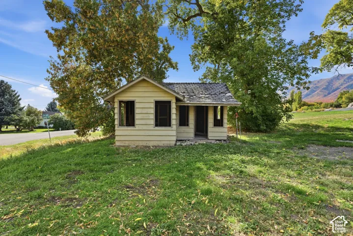 Wood-sided outbuilding with multiple windows, set on a grassy expanse