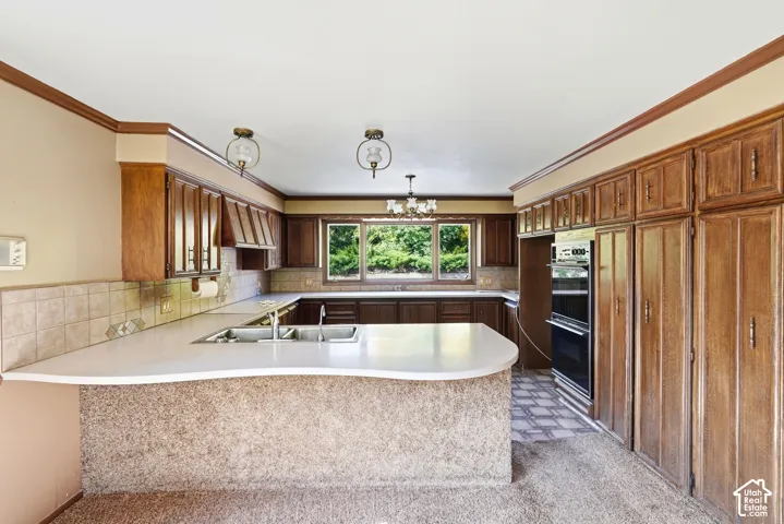 Extensive wood cabinetry, double wall ovens, tile backsplash, built-in double sink, and a large window