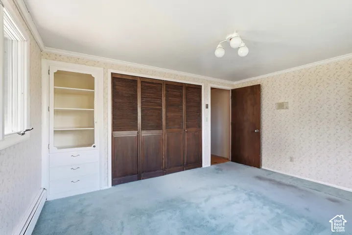 Built-in shelving with glass-front cabinet, wood louvered closet doors, and broadloom carpeting
