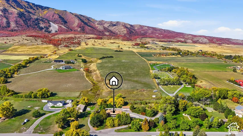 Expansive property with mature trees, green fields, and mountainous terrain