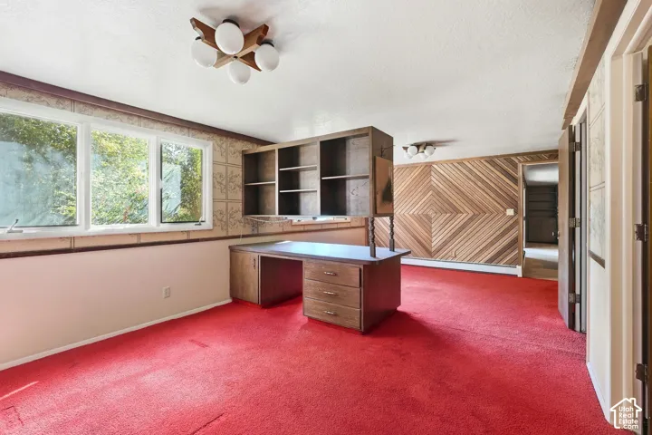Built-in desk with shelving, multiple windows, patterned accent wall, and ceiling-mounted light fixtures