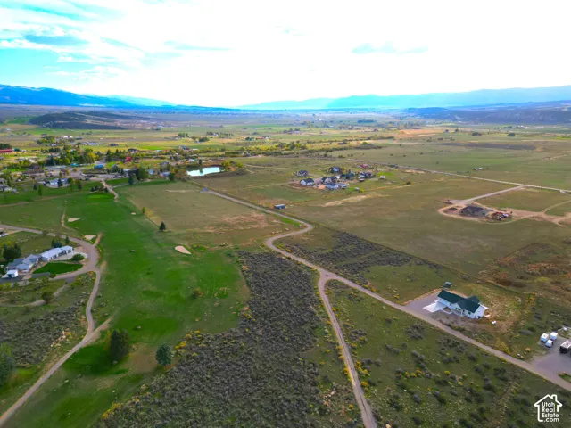 Expansive property with a verdant landscape, featuring a large body of water, distant mountain ranges, and scattered residential structures