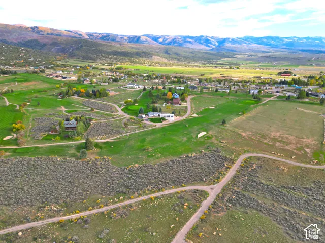 Expansive golf course property with distant mountain backdrop, featuring scattered residential structures, and established landscaping