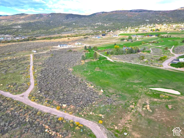 Expansive lot with green landscape, natural terrain, mountain backdrop, and scattered residential properties