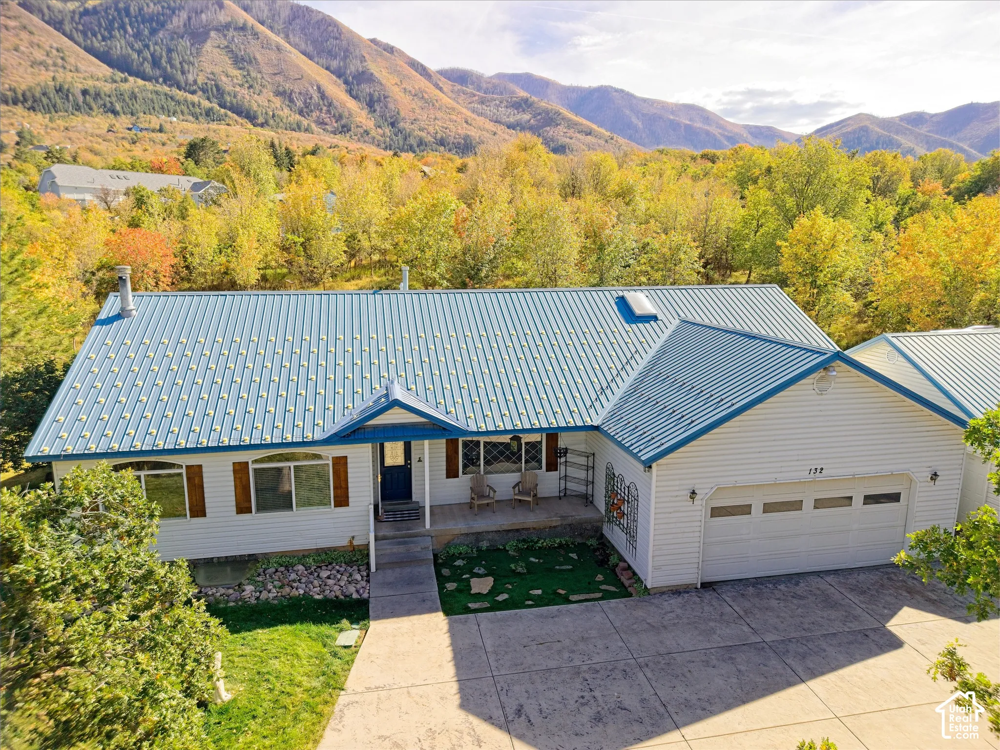 White siding exterior with a blue metal roof, an attached two-car garage, and a concrete driveway