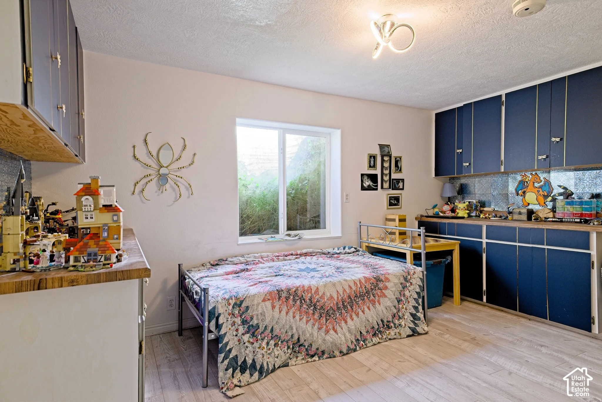 Wood-finish flooring, recessed window, and built-in blue cabinetry with light wood-finish countertops
