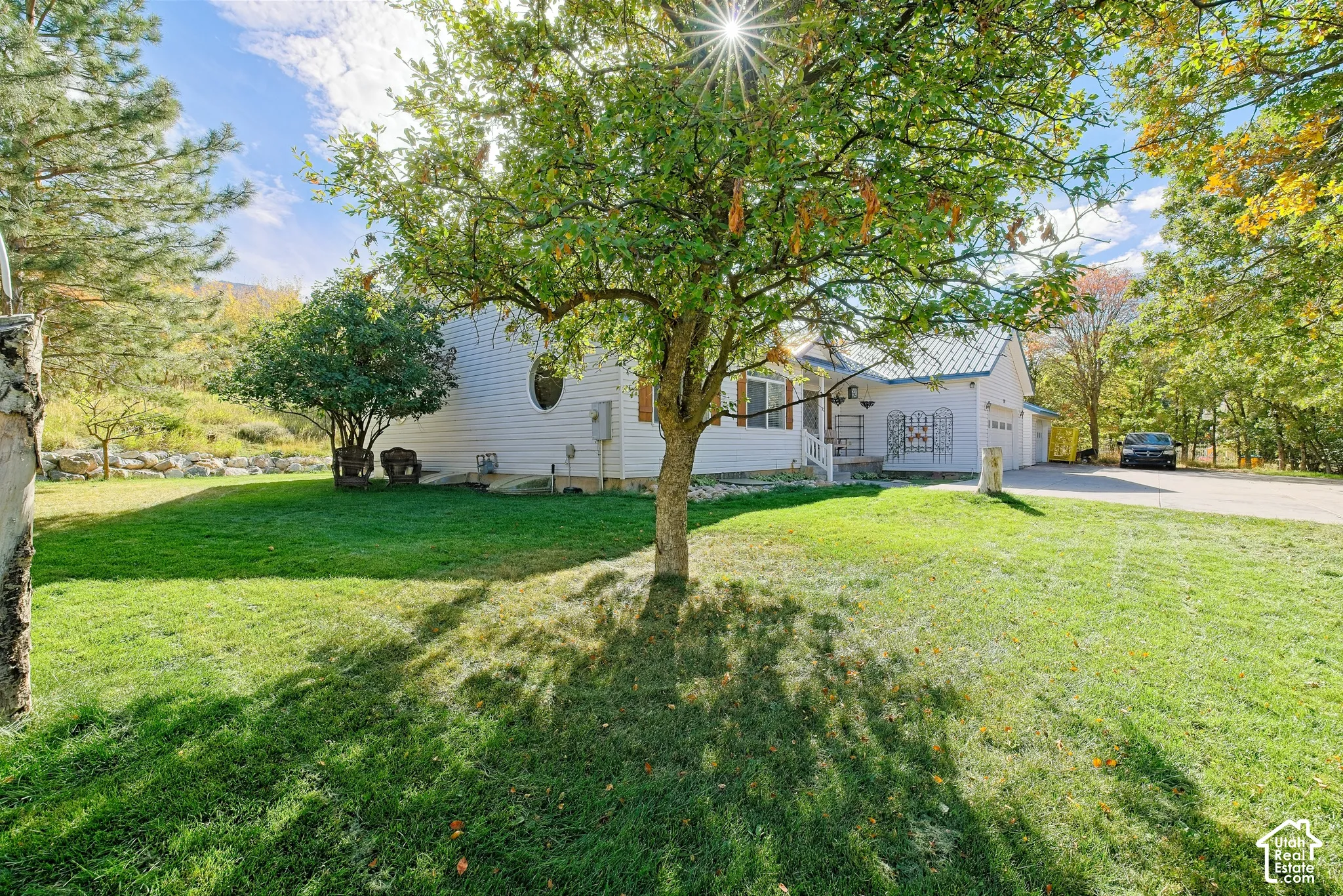 White exterior featuring a light-colored roof, attached garage, and a lush green lawn