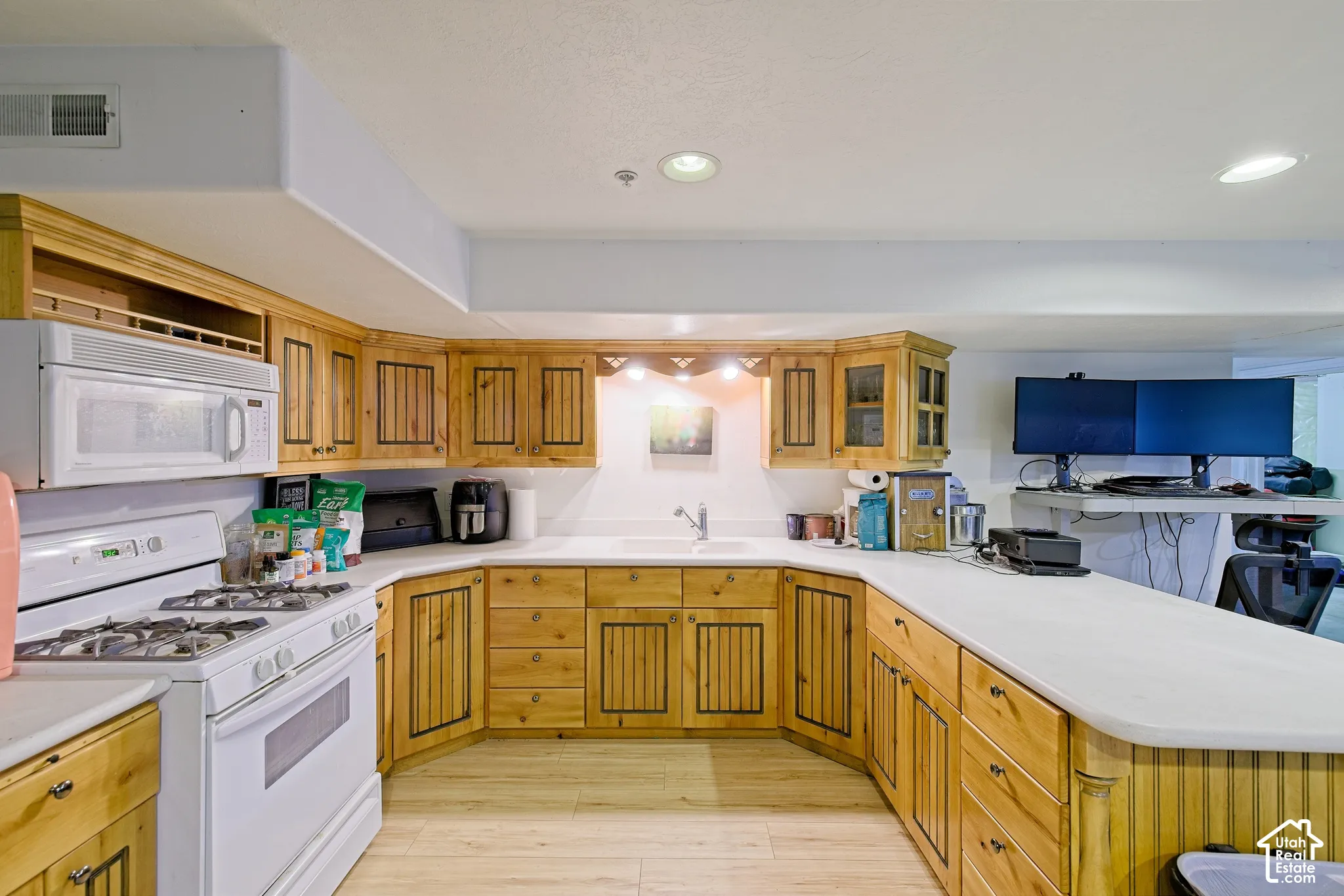 U-shaped kitchen featuring wood cabinetry, white countertops, built-in microwave, and a gas range
