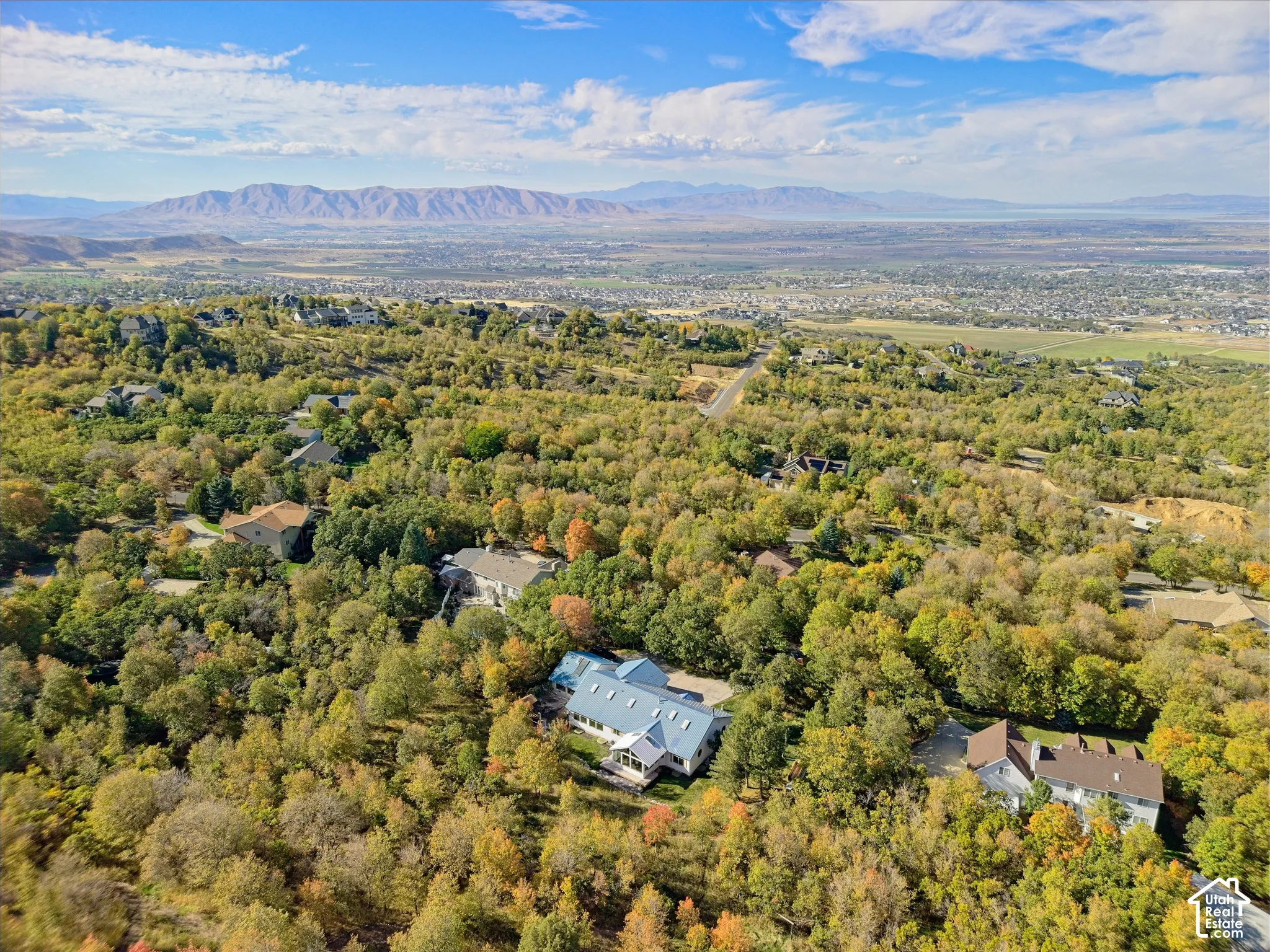 Expansive natural surroundings with a distant mountain range and a residential property featuring a light-colored roof