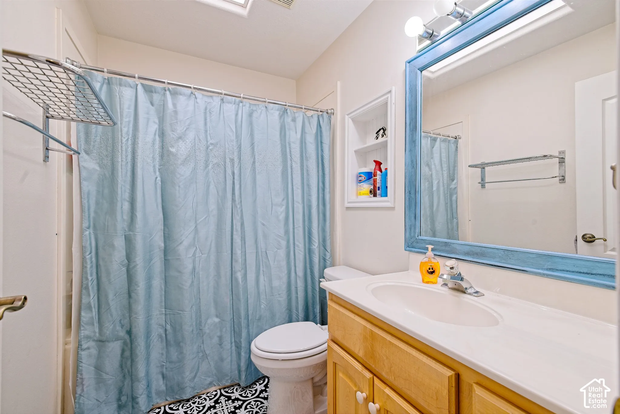 Bathroom featuring a built-in vanity with light wood cabinetry, an integrated sink, and a framed mirror