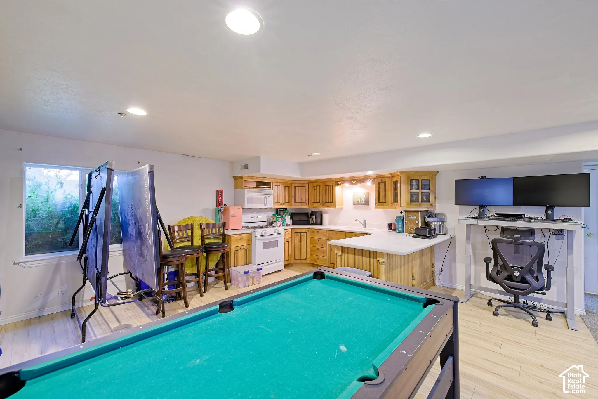 Recessed lighting, wood-finish flooring, light wood cabinetry, white countertops, and a full-size window