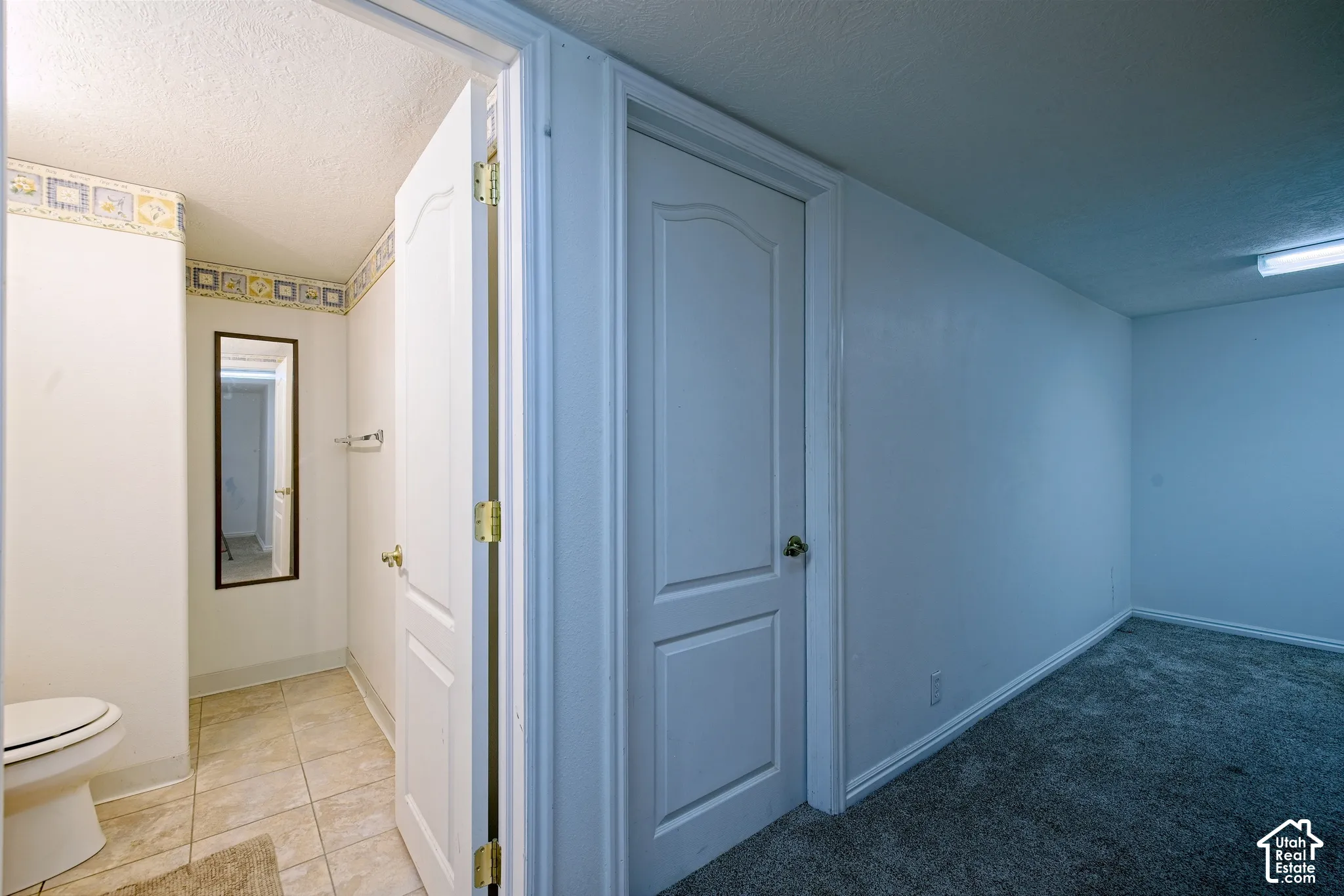 Full-length mirror, tiled flooring, white painted walls, and textured ceiling