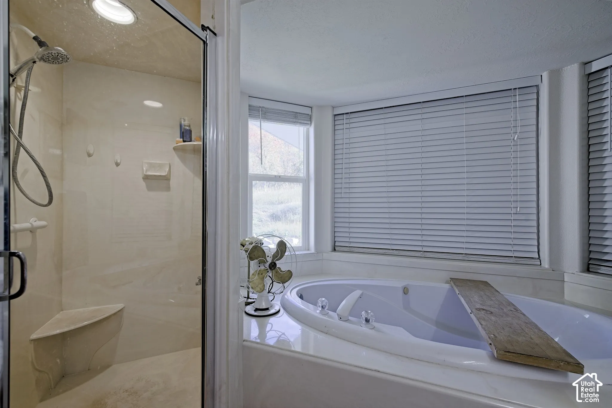 Enclosed shower with a built-in bench, recessed lighting, and a garden tub with surrounding windows