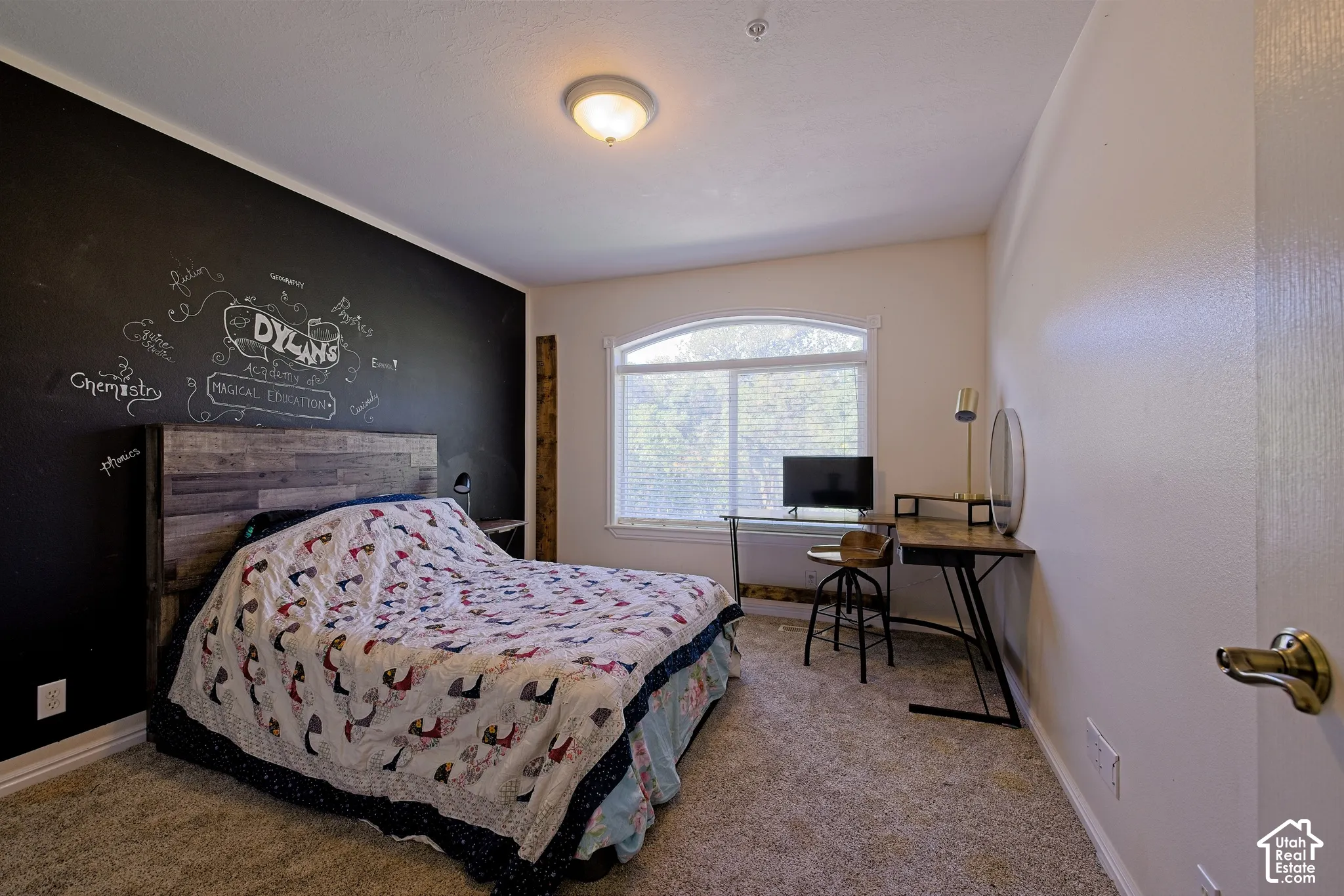 Arched window with blinds, overhead flush mount lighting, and broadloom carpet