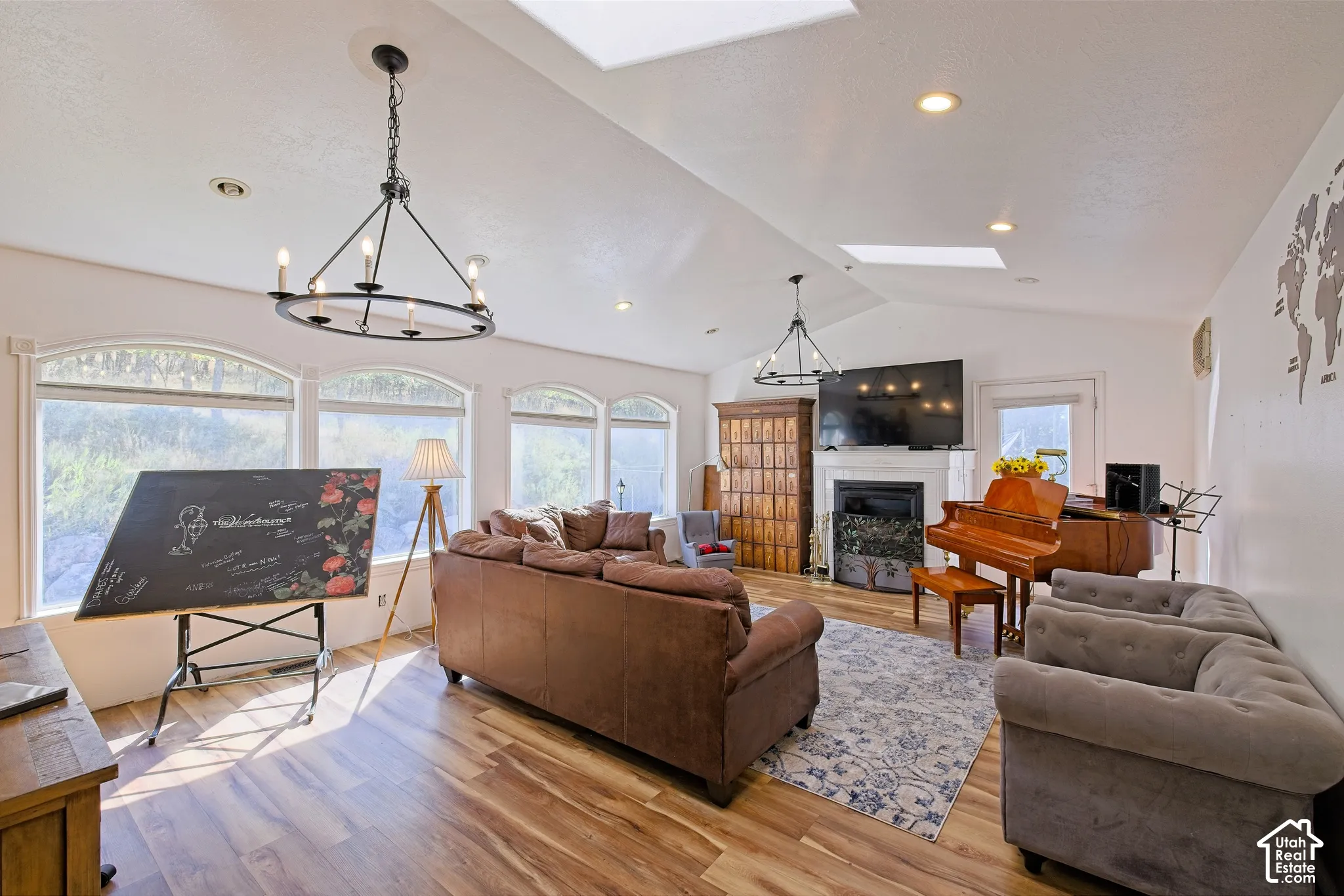 Vaulted ceilings, wood-finish flooring, multiple arched windows, recessed lighting, and a fireplace with a mantel
