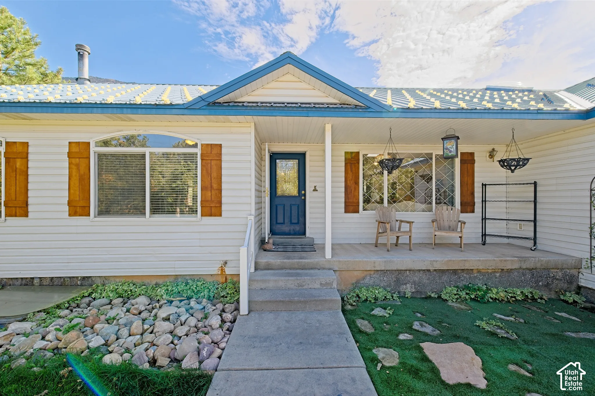 White siding exterior with a blue metal roof and a covered porch