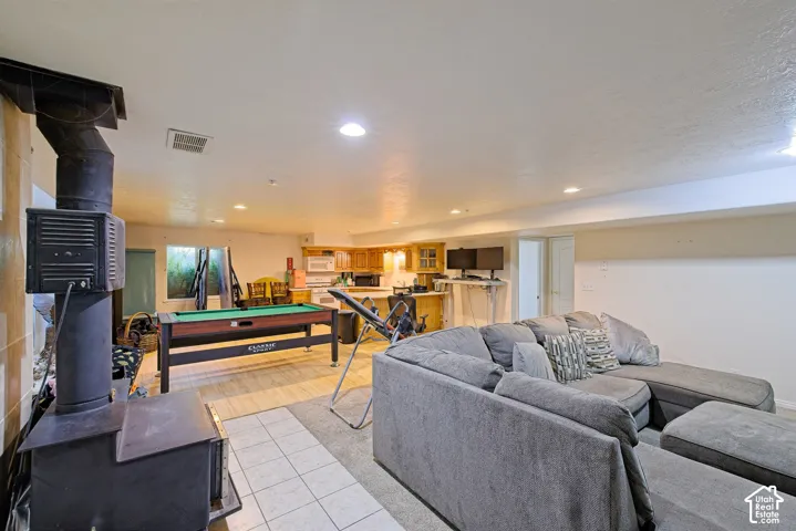 Open-concept living space with a wood-burning stove, recessed lighting, and a kitchen area featuring wood-finish cabinetry