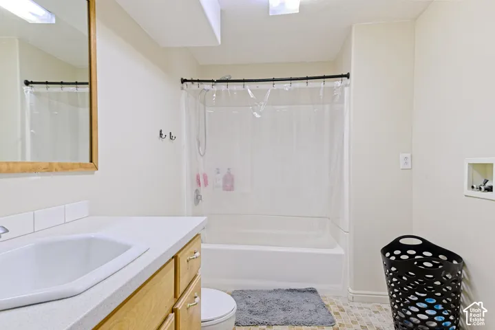 Bathroom featuring a built-in vanity with a composite countertop and integrated sink, a framed mirror, a bathtub with an overhead shower, and mosaic tile flooring