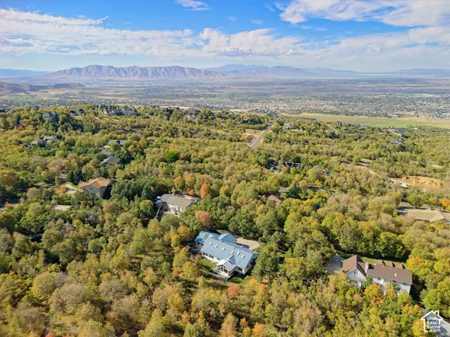 Expansive natural surroundings with a distant mountain range and a residential property featuring a light-colored roof