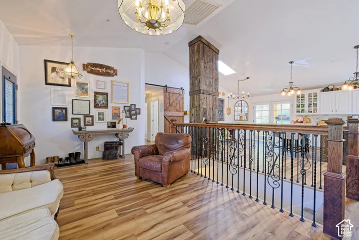 Wood-finish flooring throughout, wrought iron and wood railing, decorative barn door, and a skylight