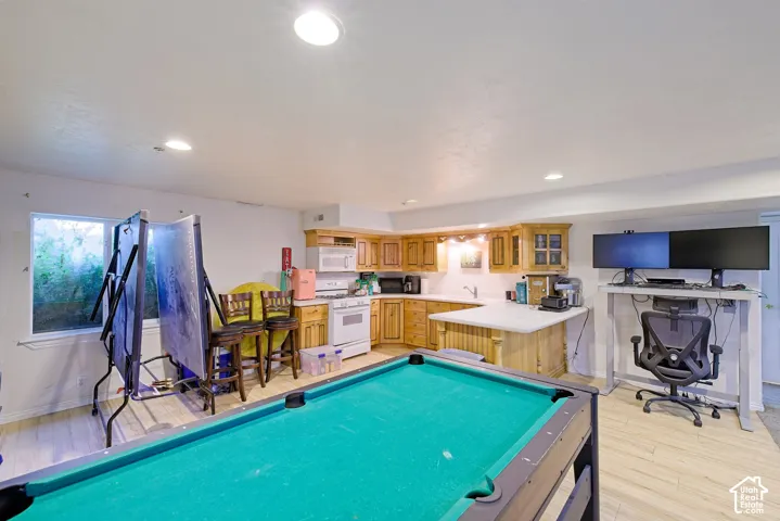 Recessed lighting, wood-finish flooring, light wood cabinetry, white countertops, and a full-size window