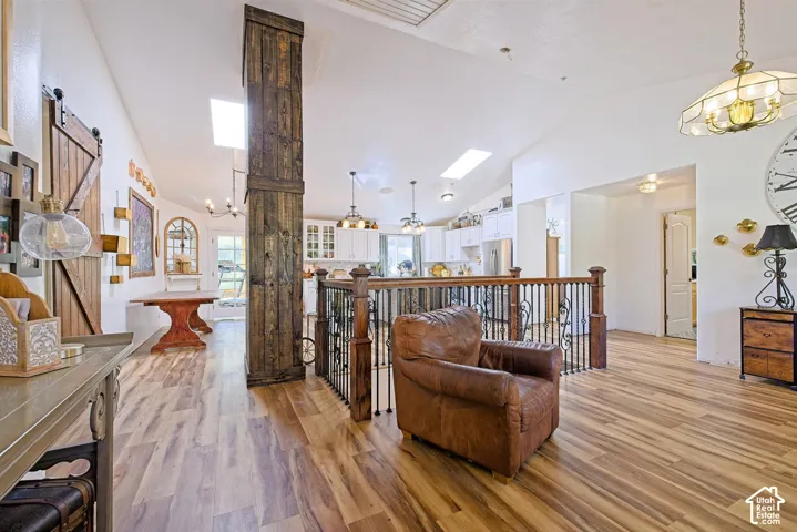 Vaulted ceilings, wood-finish flooring, skylights, white cabinetry, and a wood-wrapped structural beam