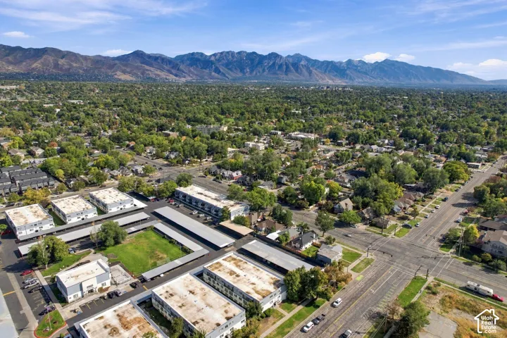 Expansive neighborhood featuring mature trees, residential properties, commercial structures, and mountain scenery
