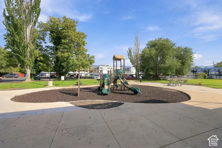 Recreational area featuring a playground structure with slides and swings, surrounded by woodchip ground cover