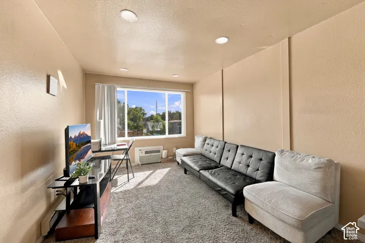 Recessed ceiling lighting, large window with natural light, window-mounted air conditioning unit, and textured wall finish