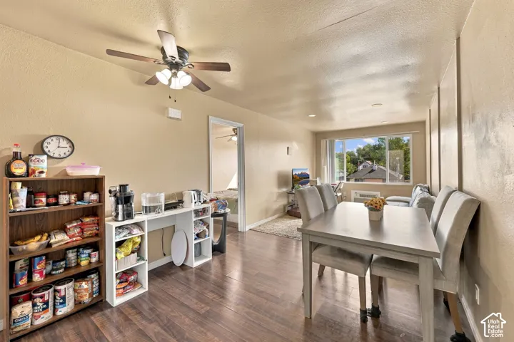 Wood-finish flooring throughout, ceiling fan with integrated lighting, built-in shelving, and a large window providing natural illumination