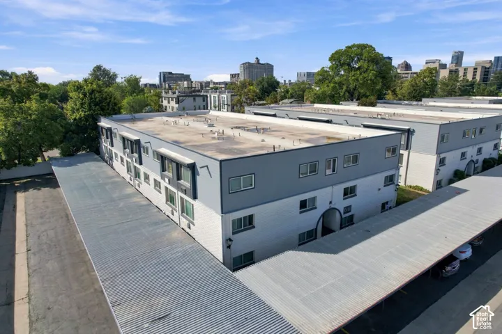 Multi-story building featuring a white and gray exterior, multiple windows, and covered parking structures