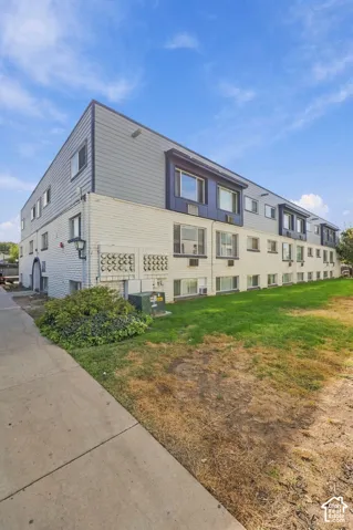 Three-story multi-family building featuring a white brick first level and gray siding on upper levels