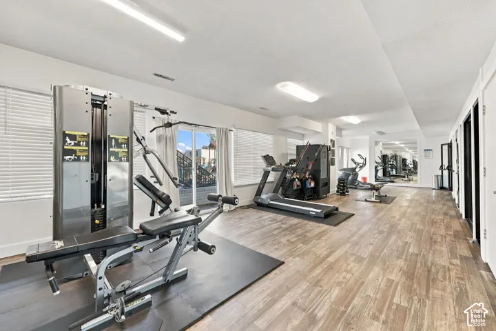 Open-concept room featuring wood-finish flooring, ample natural light from multiple windows, recessed lighting, and a mirrored wall