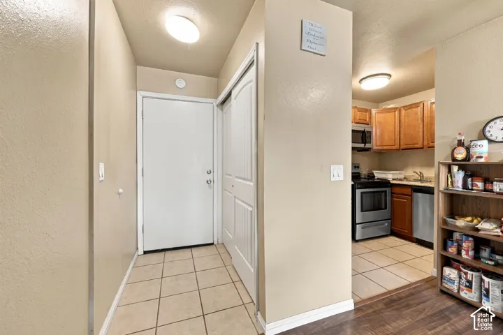 Kitchen featuring wood-finish cabinetry, stainless steel appliances, and a tile floor