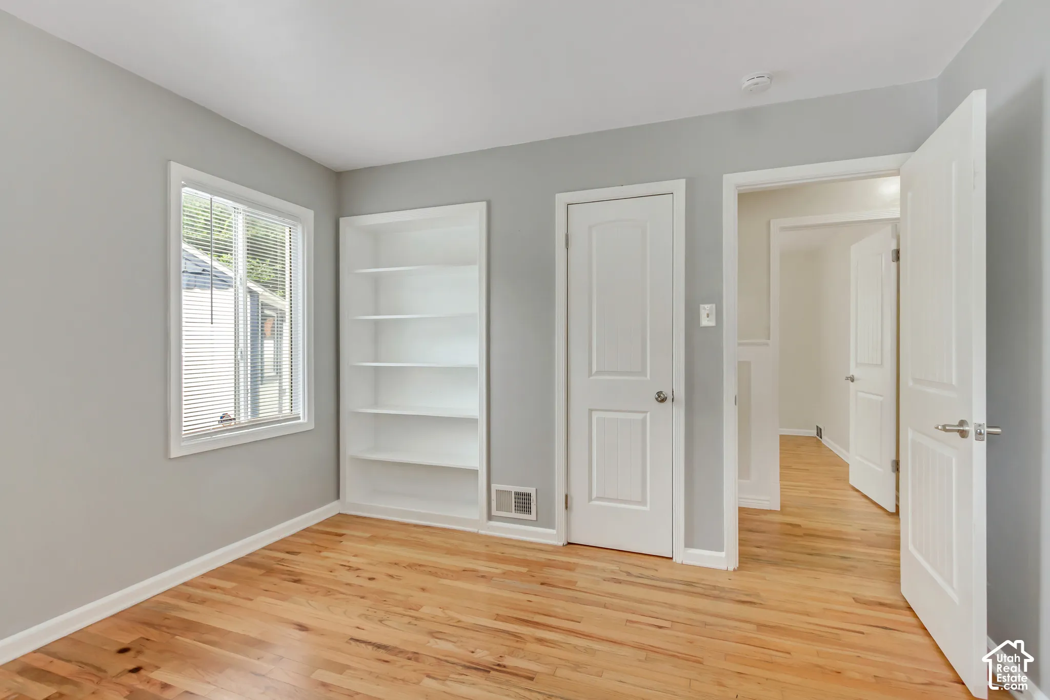 Wood-finish flooring, built-in shelving, and light gray wall paint