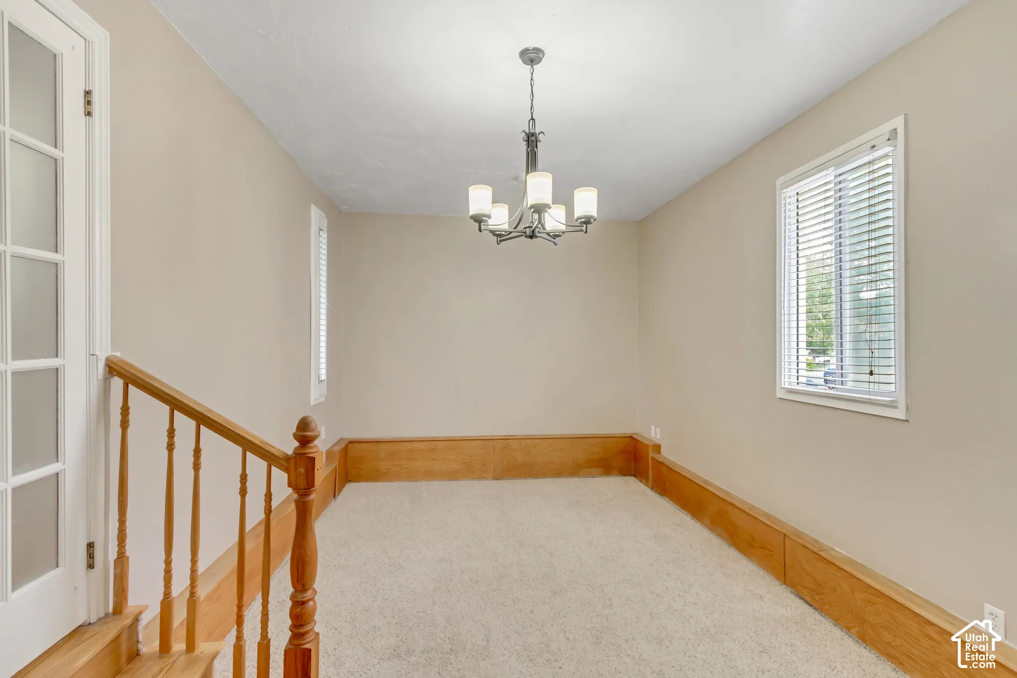 Plush carpeted room featuring a chandelier and wood paneling